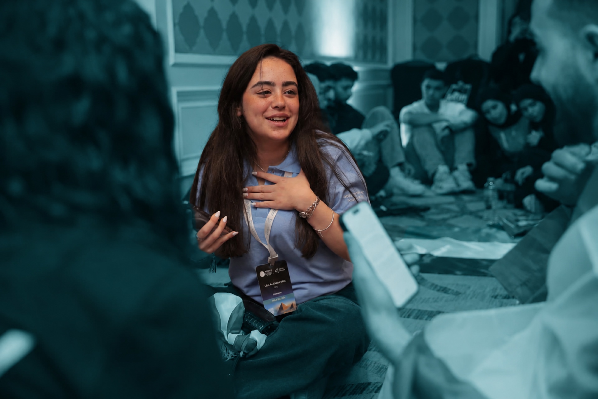 A student in a blue polo talking with her team on the floor