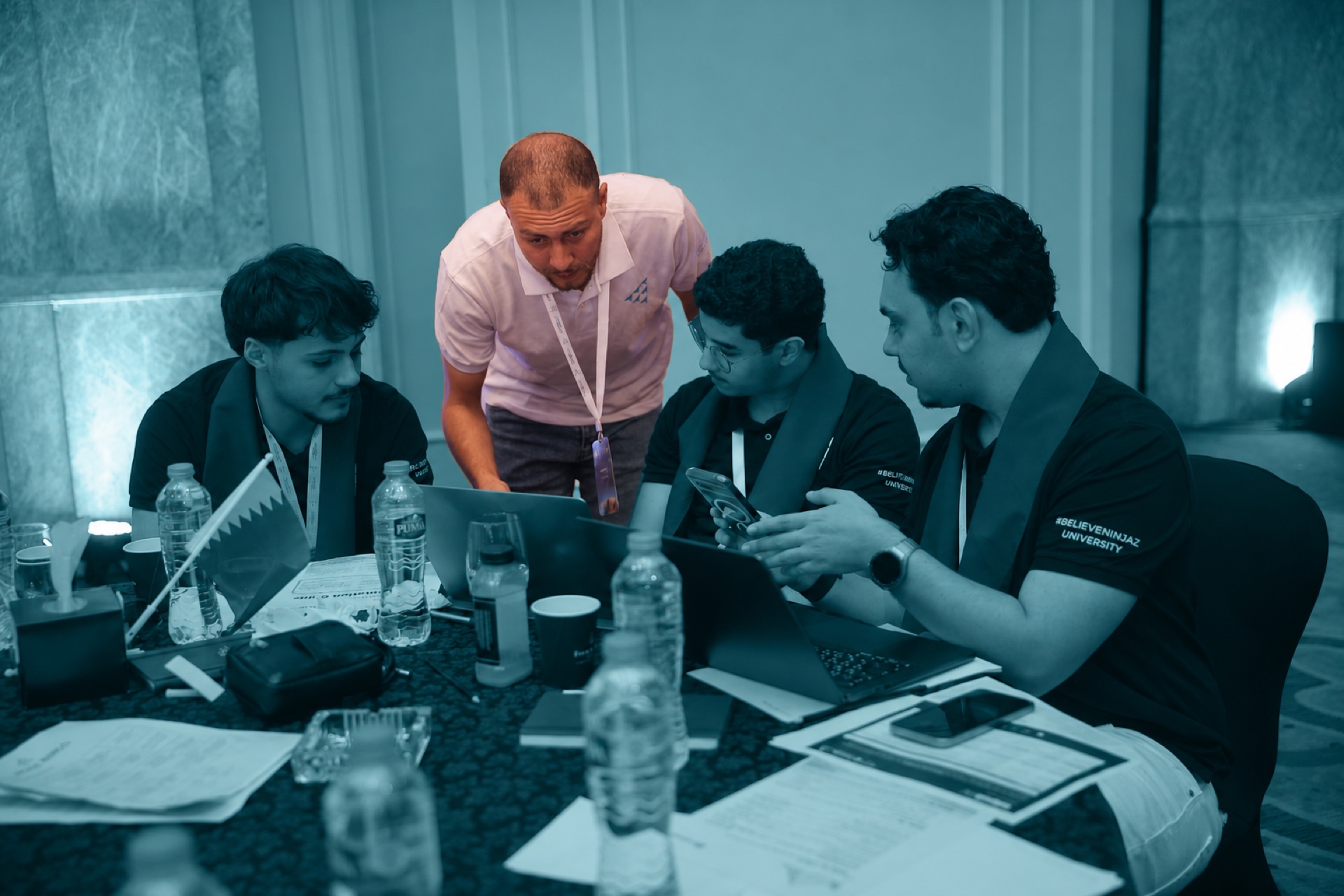 A mentor guiding a student team around a laptop